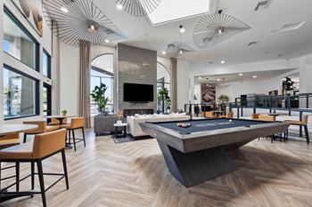 a view of the clubhouse with a pool table in the foreground and tables and chairs in the